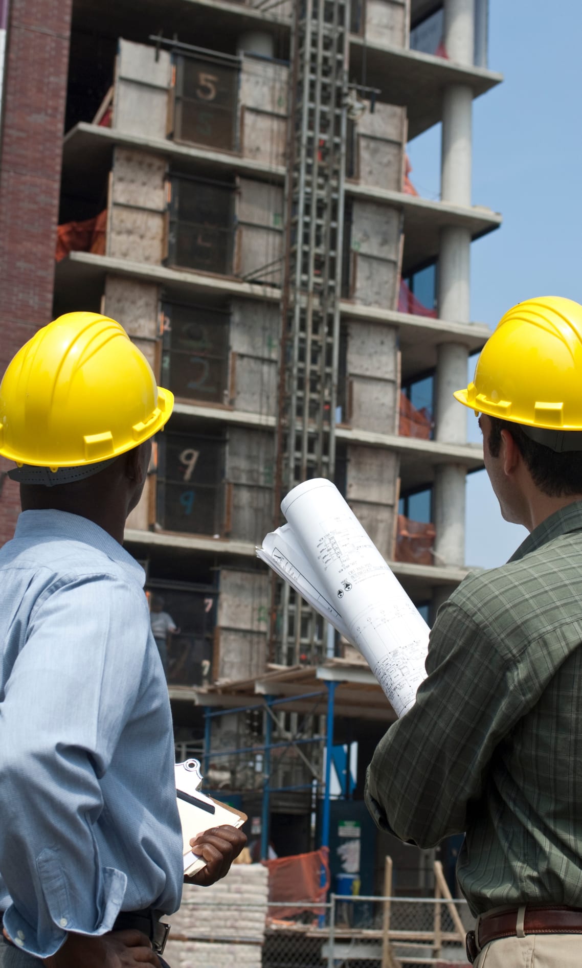 مهندسان يرتديان خوذات الأمان يراجعان مخططات المشروع في الموقع